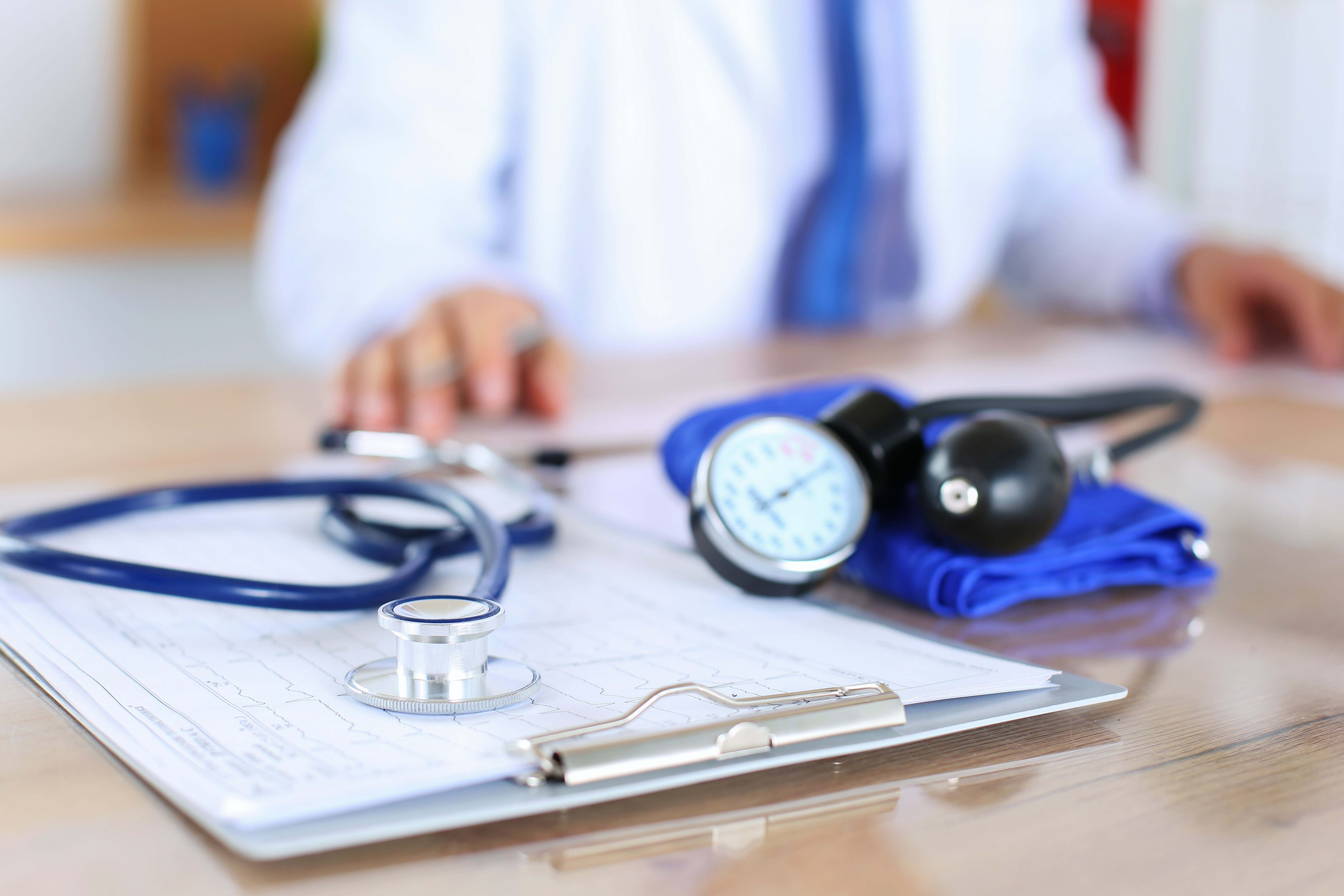 Clipboard, stethescope, and blood-pressure band on the desk of a healthcare professional